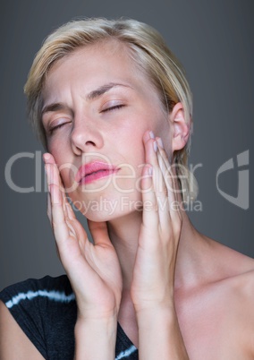 Close up of woman rubbing face against grey background