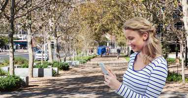 Smiling woman using tablet PC in park