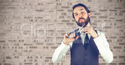 Hipster cutting beard against wall