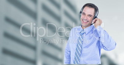 Portrait of happy male customer care representative wearing headphones against building