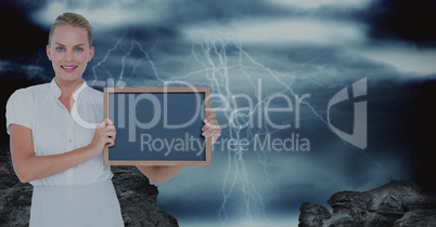 Confident businesswoman holding blank slate against thunderstorm