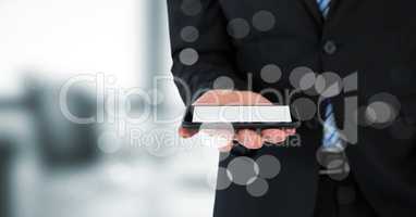 Business man mid section with phone behind bokeh against blurry grey office