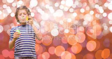 Boy playing with soap bubbles over bokeh