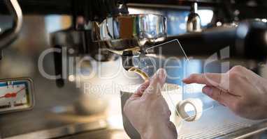 Hands photographing coffee machine through transparent device