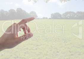 Hand touching landscape with field and sky