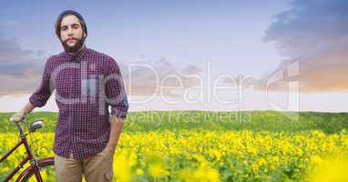 Male hipster with bicycle on flowering field