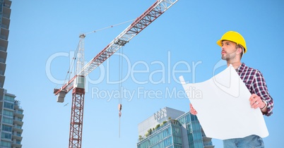 Low angle view of architect holding blueprint by crane