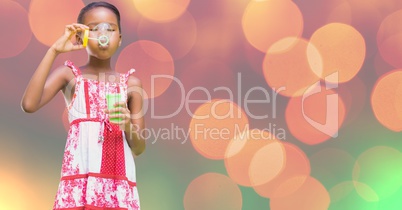 Girl playing with soap bubbles against bokeh