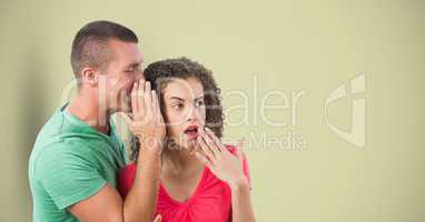 Man whispering in woman's ear over colored background