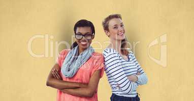 Portrait of confident businesswomen standing arms crossed against yellow background