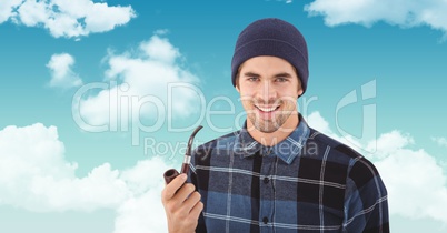 Smiling hipster holding smoking pipe against sky