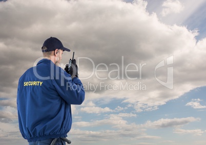 Rear view of security guard using radio against cloudy sky
