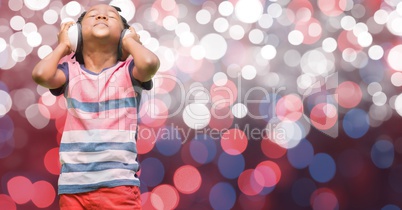 Boy listening music through headphones over glowing bokeh