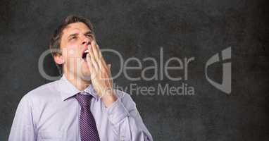 Tired businessman yawning against blackboard