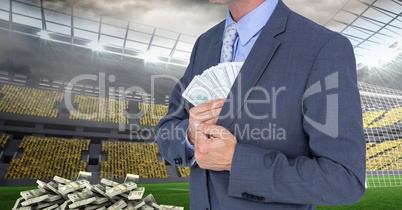 Midsection of businessman hiding money at soccer stadium representing corruption concept