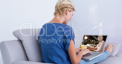 Rear view of woman video conferencing on sofa