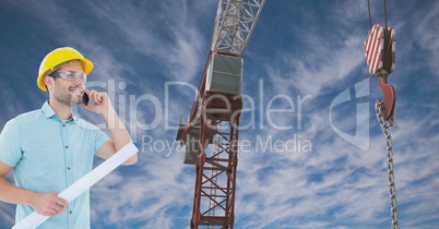 Architect using mobile phone while holding blue print by crane against sky