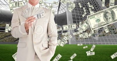 Midsection of businessman showing money at football stadium representing corruption