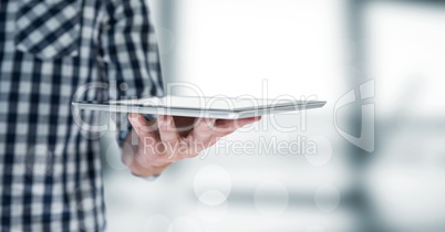 Man mid section with tablet behind bokeh against blurry grey window