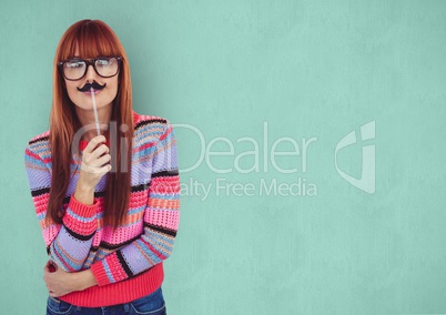 Female hipster holding artificial mustache over green background