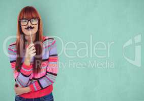 Female hipster holding artificial mustache over green background