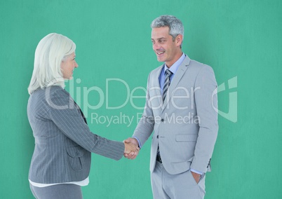 Business people shaking hands against green background