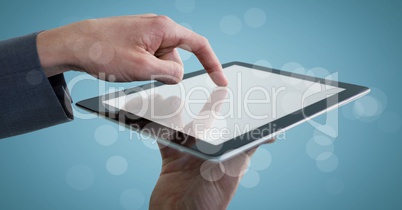 Hands touching tablet behind bokeh against blue background
