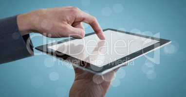 Hands touching tablet behind bokeh against blue background