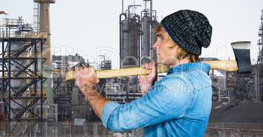 Side view of male hipster holding axe against factory