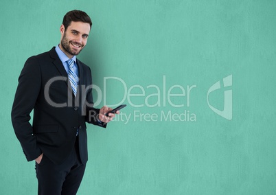 Portrait of businessman holding smart phone over turquoise background