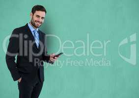 Portrait of businessman holding smart phone over turquoise background