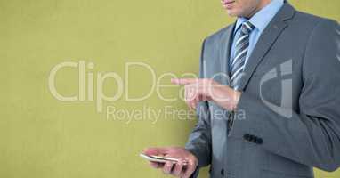 Midsection of businessman using smart phone against yellow background
