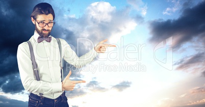 Male hipster pointing against cloudy sky