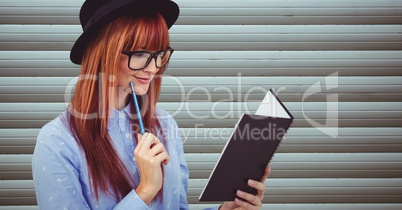 Female hipster reading book against wall