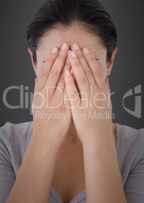 Woman hands covering face against grey wall