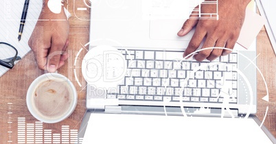 Hand using laptop while holding coffee cup