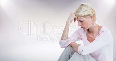 Woman sitting with head on hand against white background