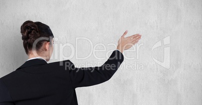 Rear view of businesswoman gesturing against wall