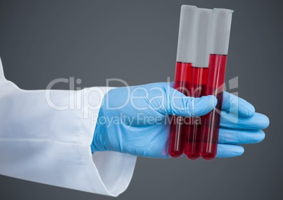 Gloved hand with red tubes against grey background
