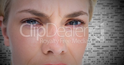 Close up of woman's angry eyes against white brick wall