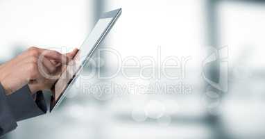 Hands touching tablet behind bokeh against blurry grey office