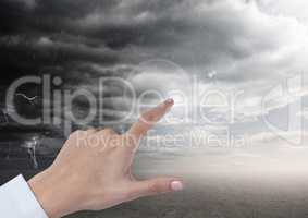 Hand pointing in air of dark stormy cloudy sky