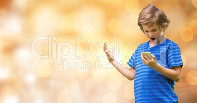 Angry boy holding mobile phone over blurred background