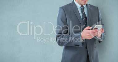 Midsection of businessman using mobile phone over blue background