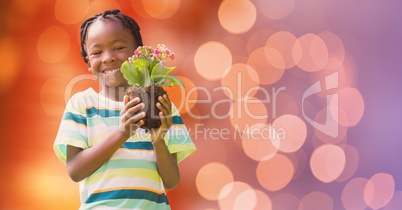 Portrait of happy boy holding flower pot over bokeh
