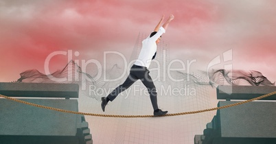 Businessman with arms raised walking on rope