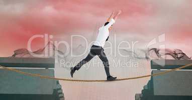 Businessman with arms raised walking on rope