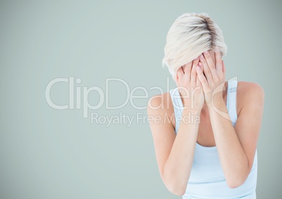 Woman crying into hands against light blue background