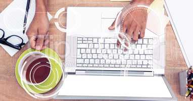 Business person using laptop while holding coffee cup