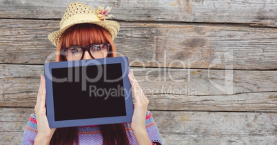 Female hipster holding tablet PC against wooden wall